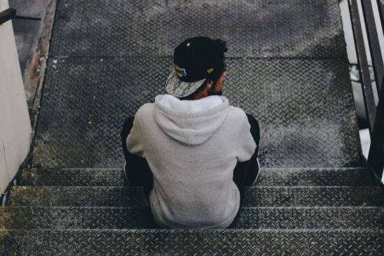 Student in a hoodie sitting alone on concrete steps
