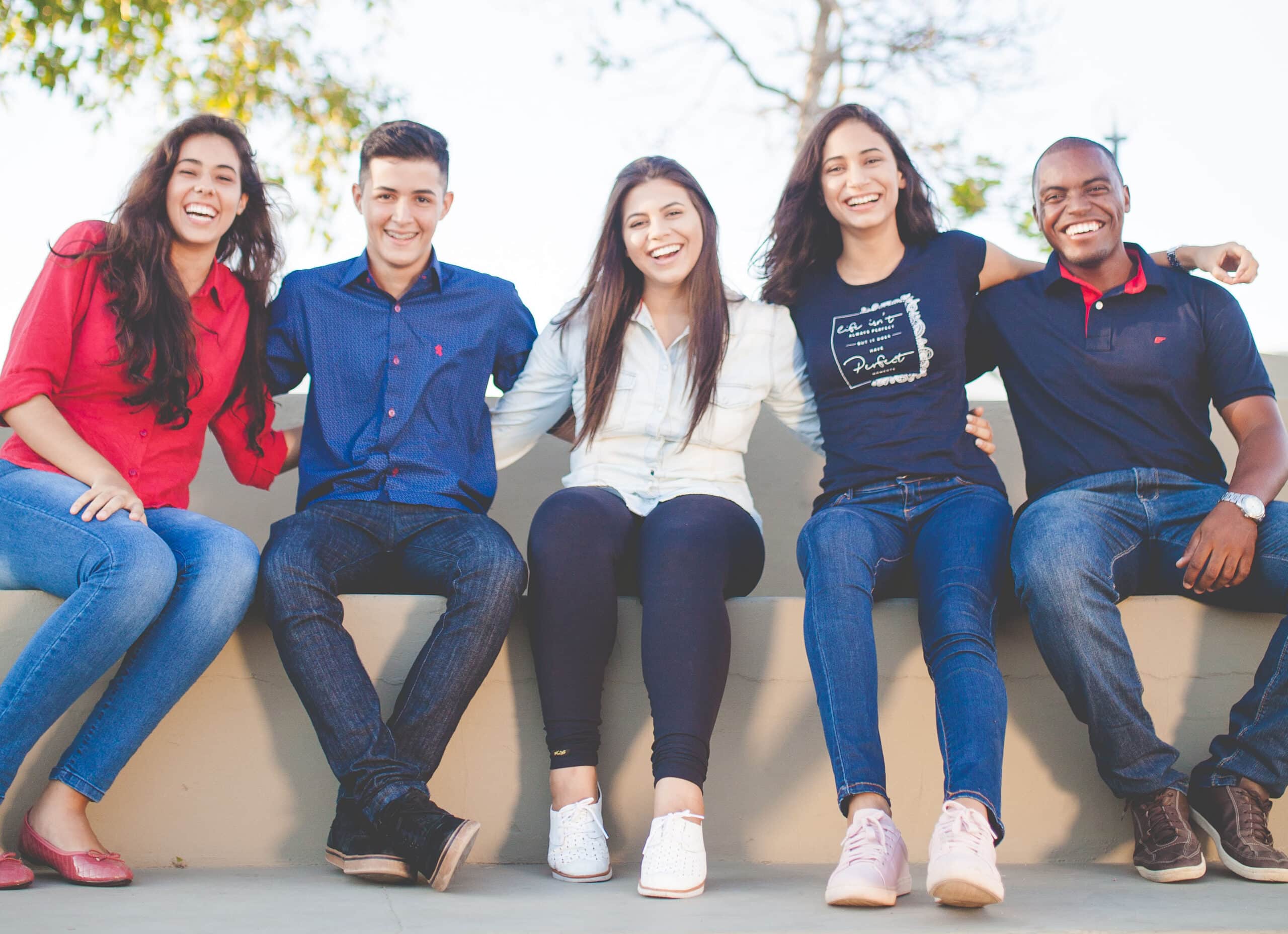 group of smiling students sitting on bench
