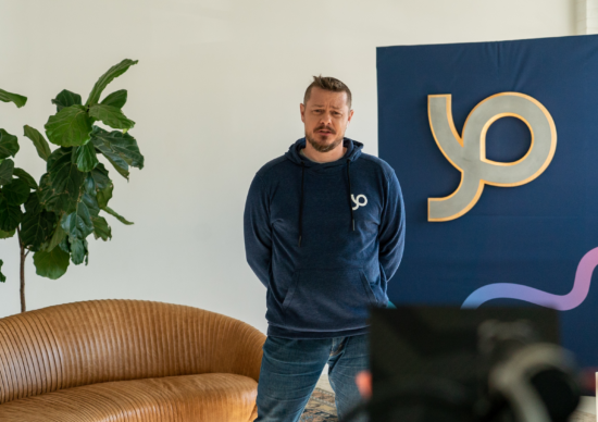 Photo of Chris Hagan standing in front of couch, tree, and Pathify sign
