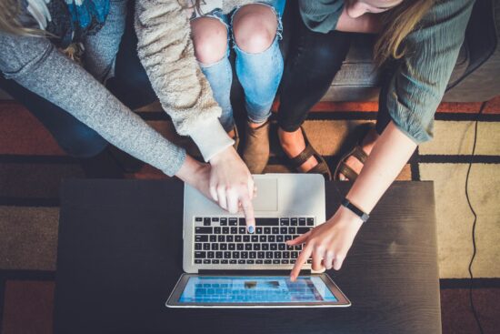 Three people pointing at laptop screen