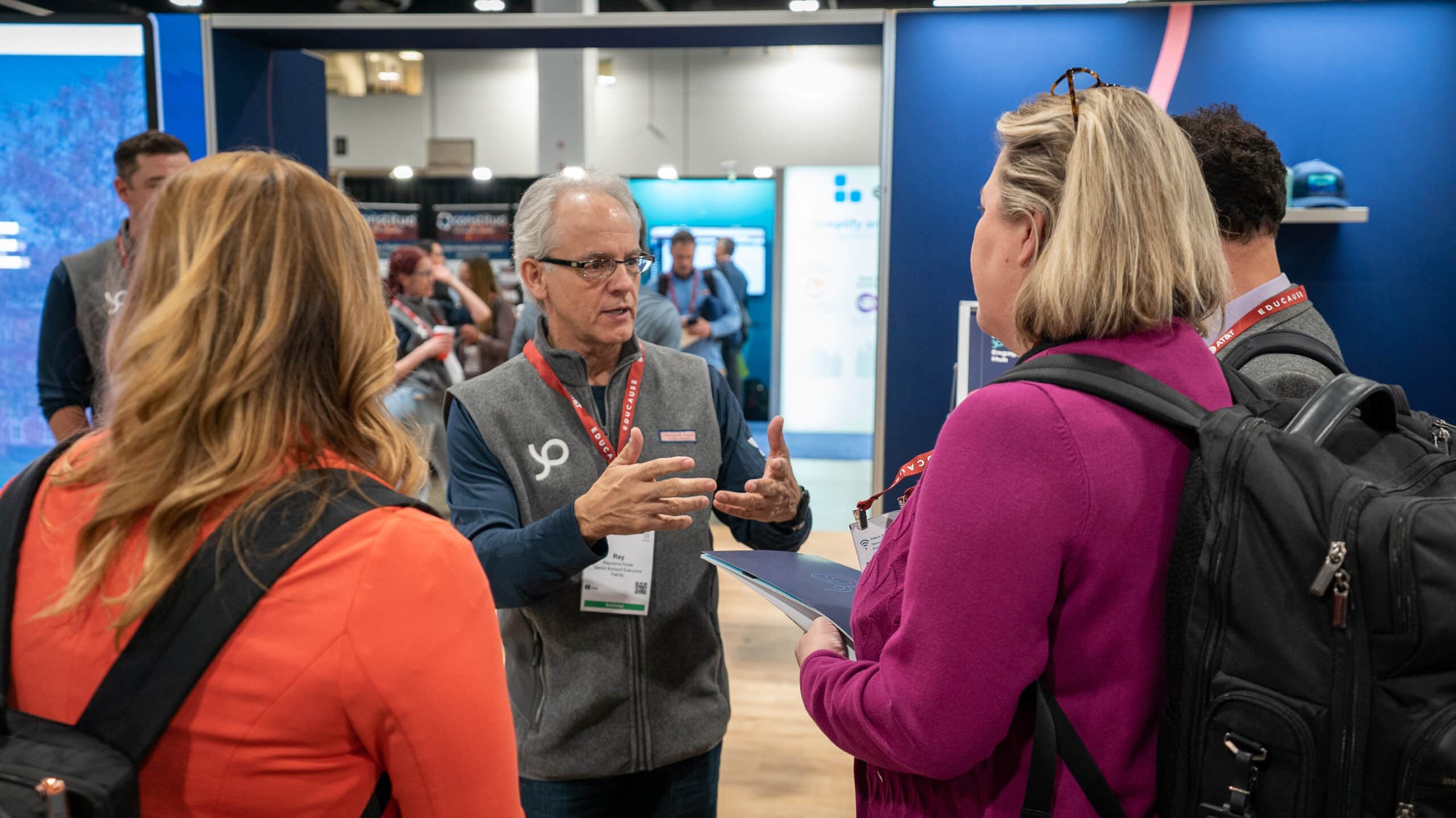 A man speaking with two women at a conference
