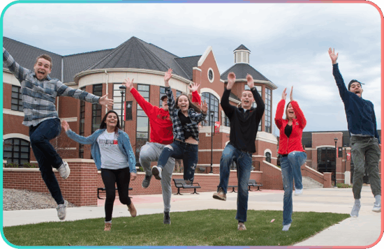 Grand View University students jumping in front of a campus building